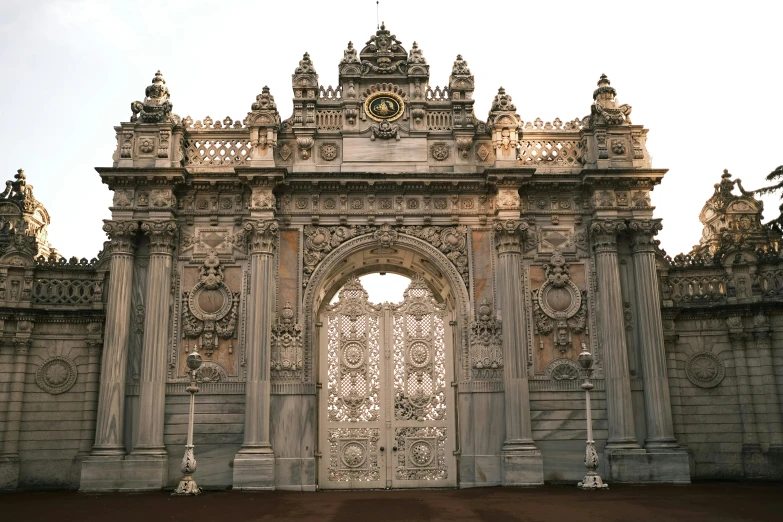 a large ornate white gate in the middle of a cement wall