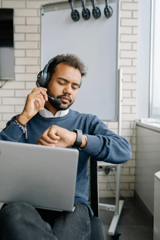 a man in a chair holding a laptop with a headset