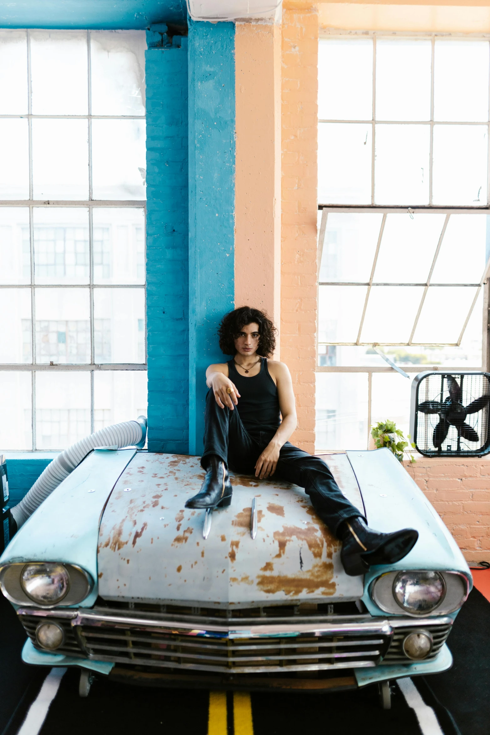 a girl sitting on top of a rusty car