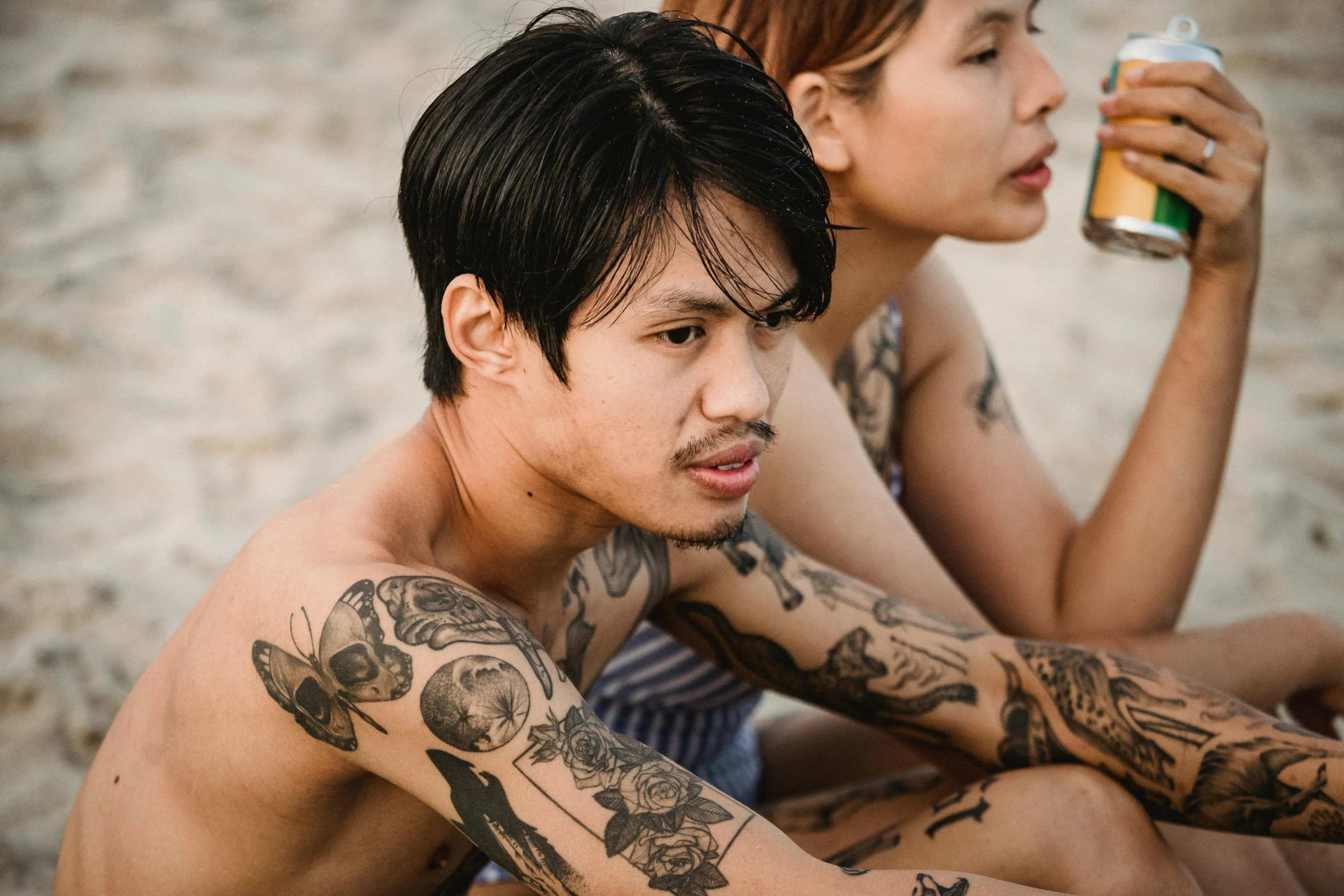 two asian men with their tattoos are drinking beer