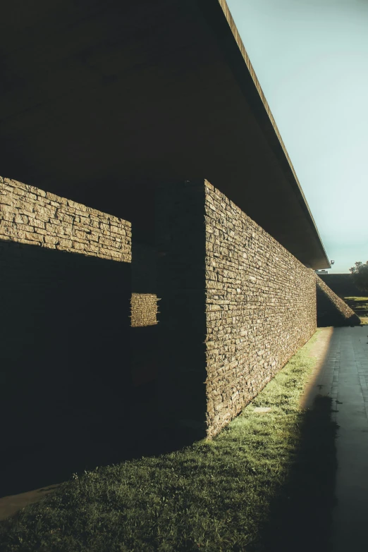 a building with a brick wall on one side and a green grass area to the other