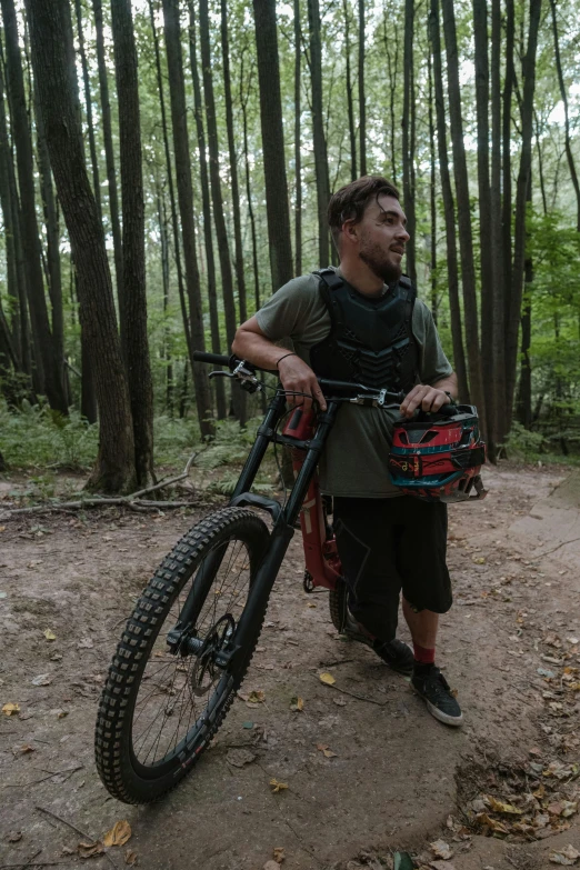 a man walking his bike in the woods