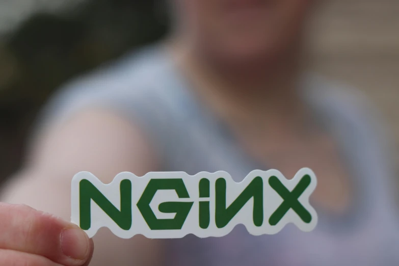 someone holding a green sticker with the name ngnx in the middle