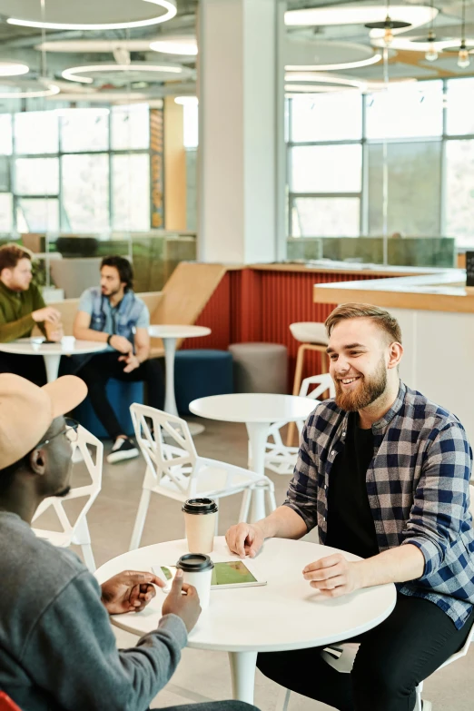 two men sitting at a table eating at an office