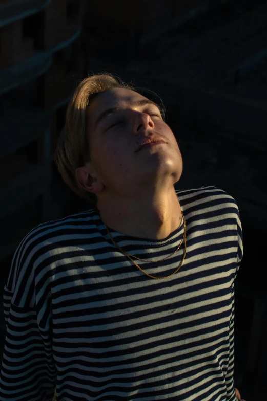 man with necklace sleeping next to wooden fence