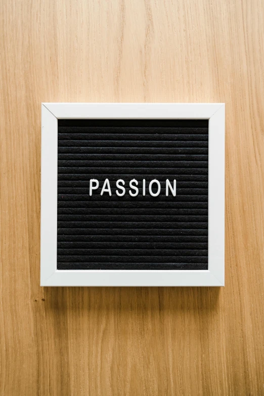 a black square frame that reads passion on a wooden surface