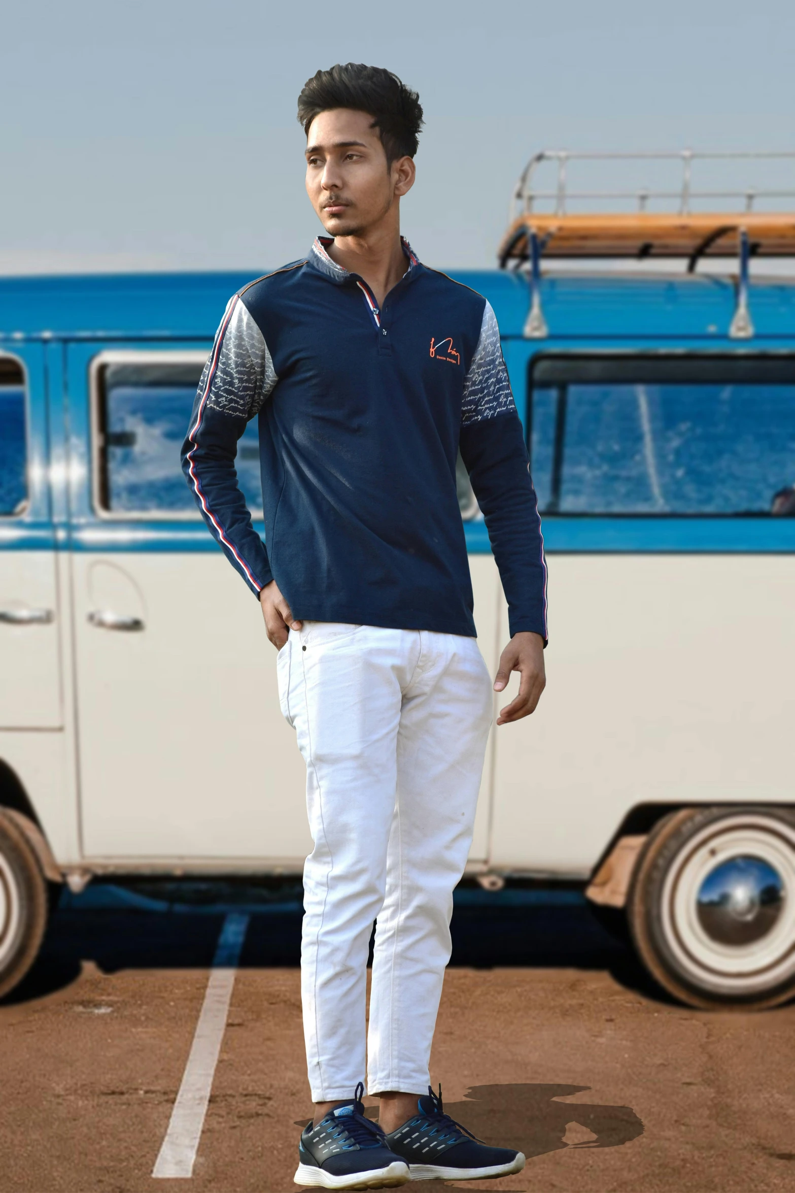 man standing in a parking lot next to an older blue and white bus