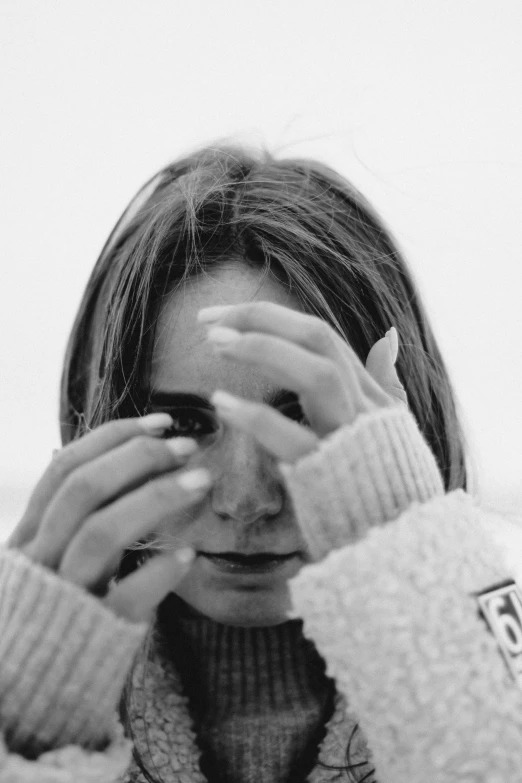 a young woman holds her hands in front of her face