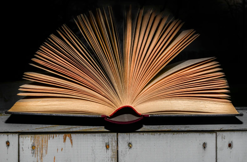 a book opened in half sitting on top of a white bench