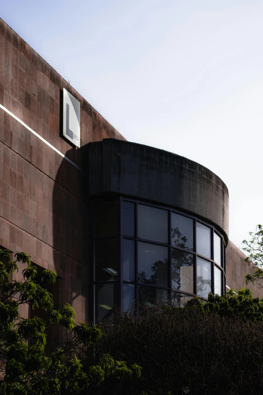 some plants and some large brick windows near a bush