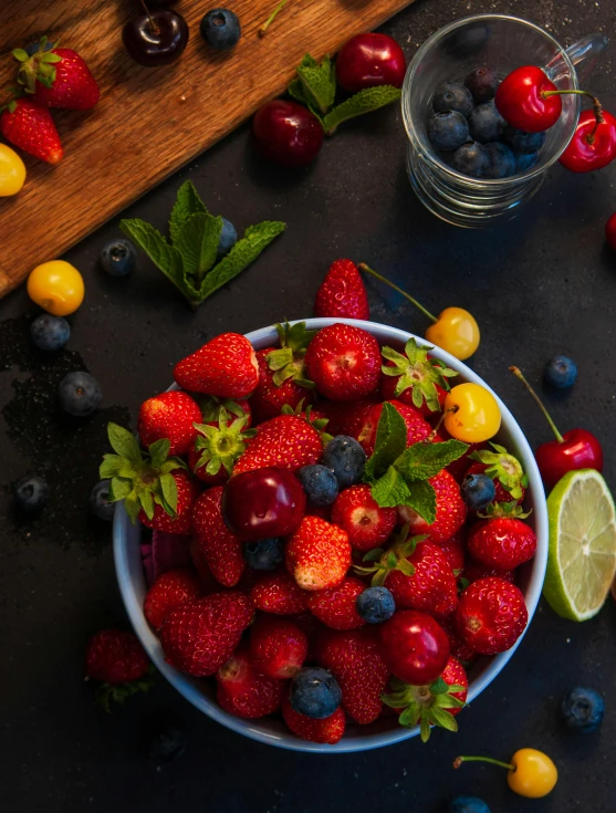 bowl of berries and lemons on black table with cherries