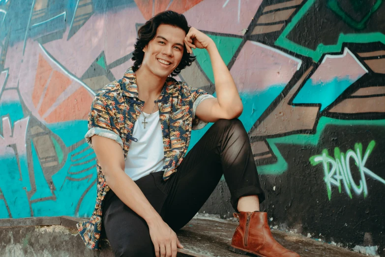 the young man is wearing brown boots and sitting on a wall