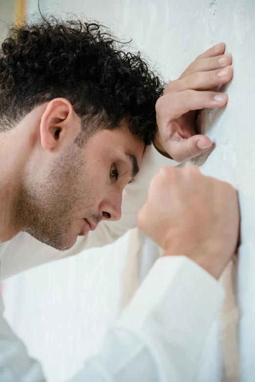 a man leaning up against a wall with his face down