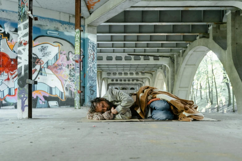 a man laying on the ground next to a long bridge