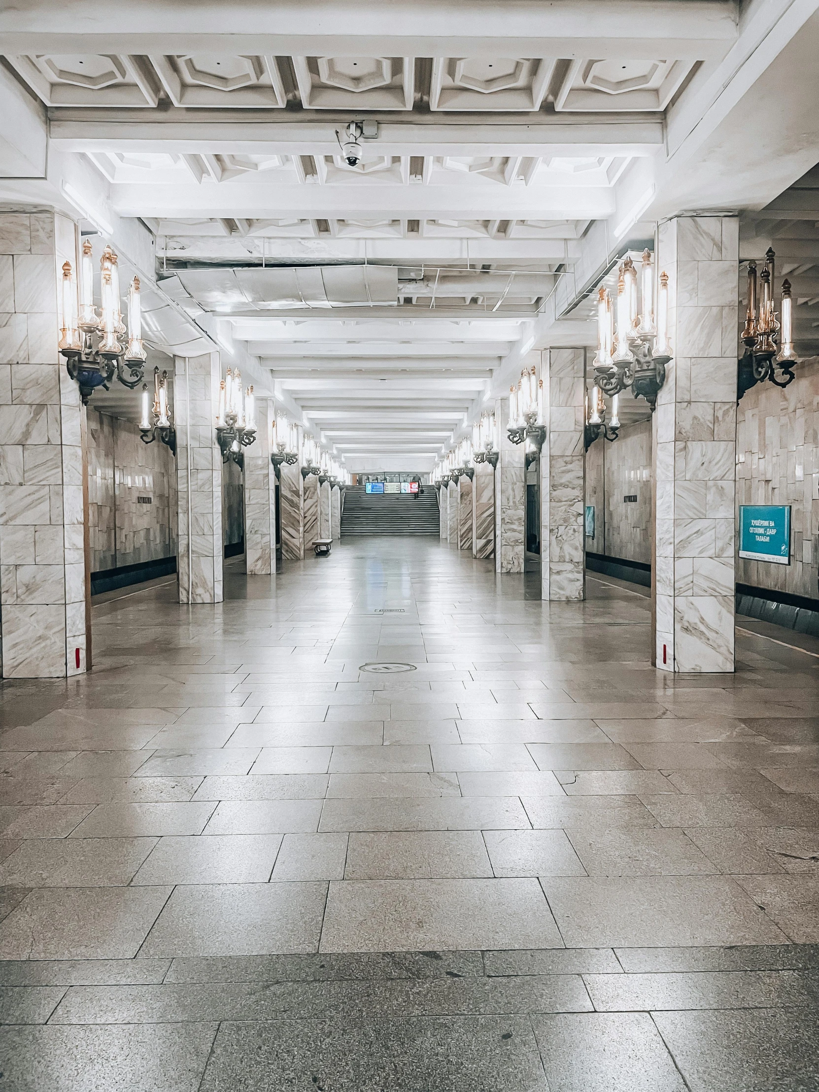 a hallway between two buildings with columns and lighting