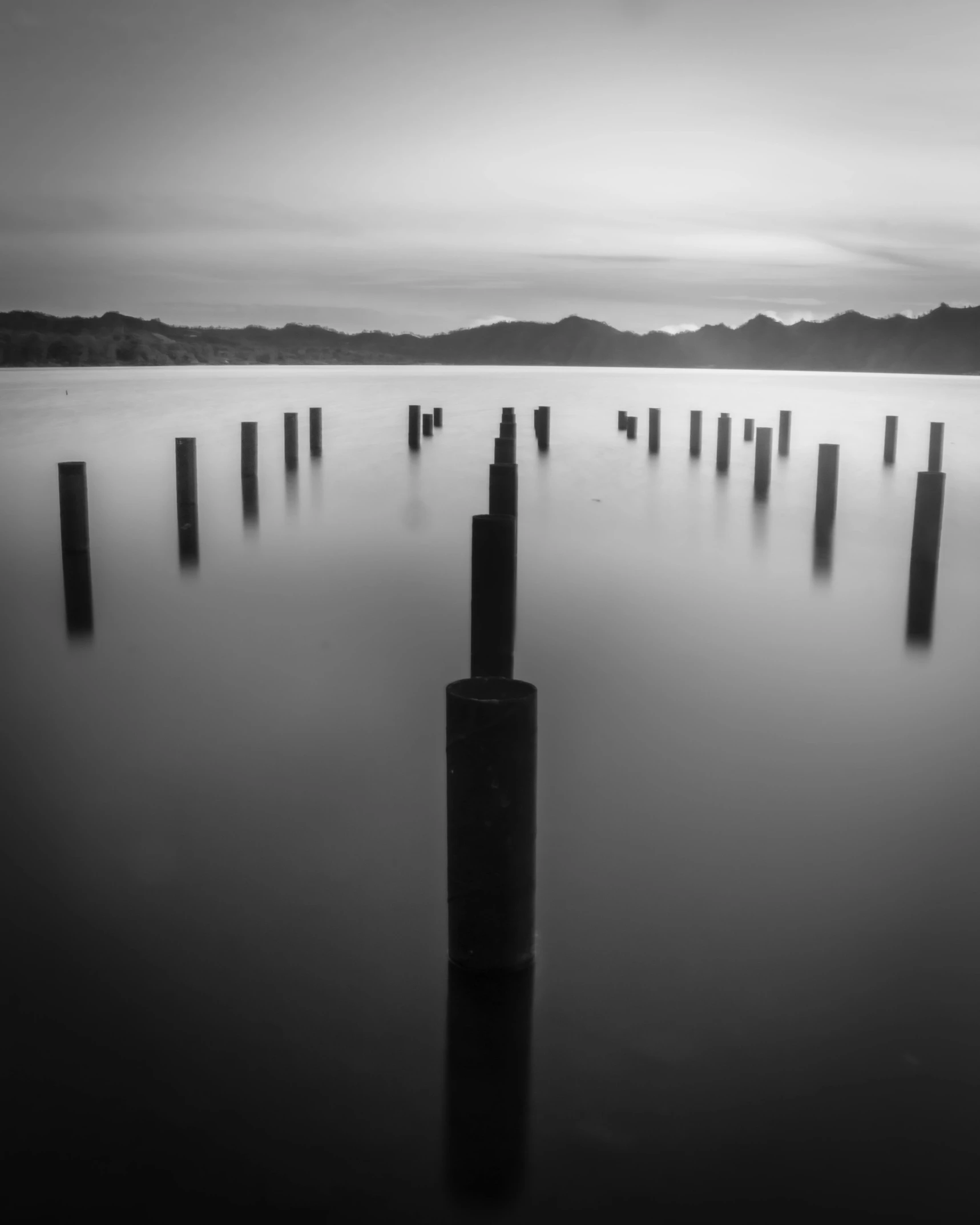 many poles sticking out from the water during a gloomy day