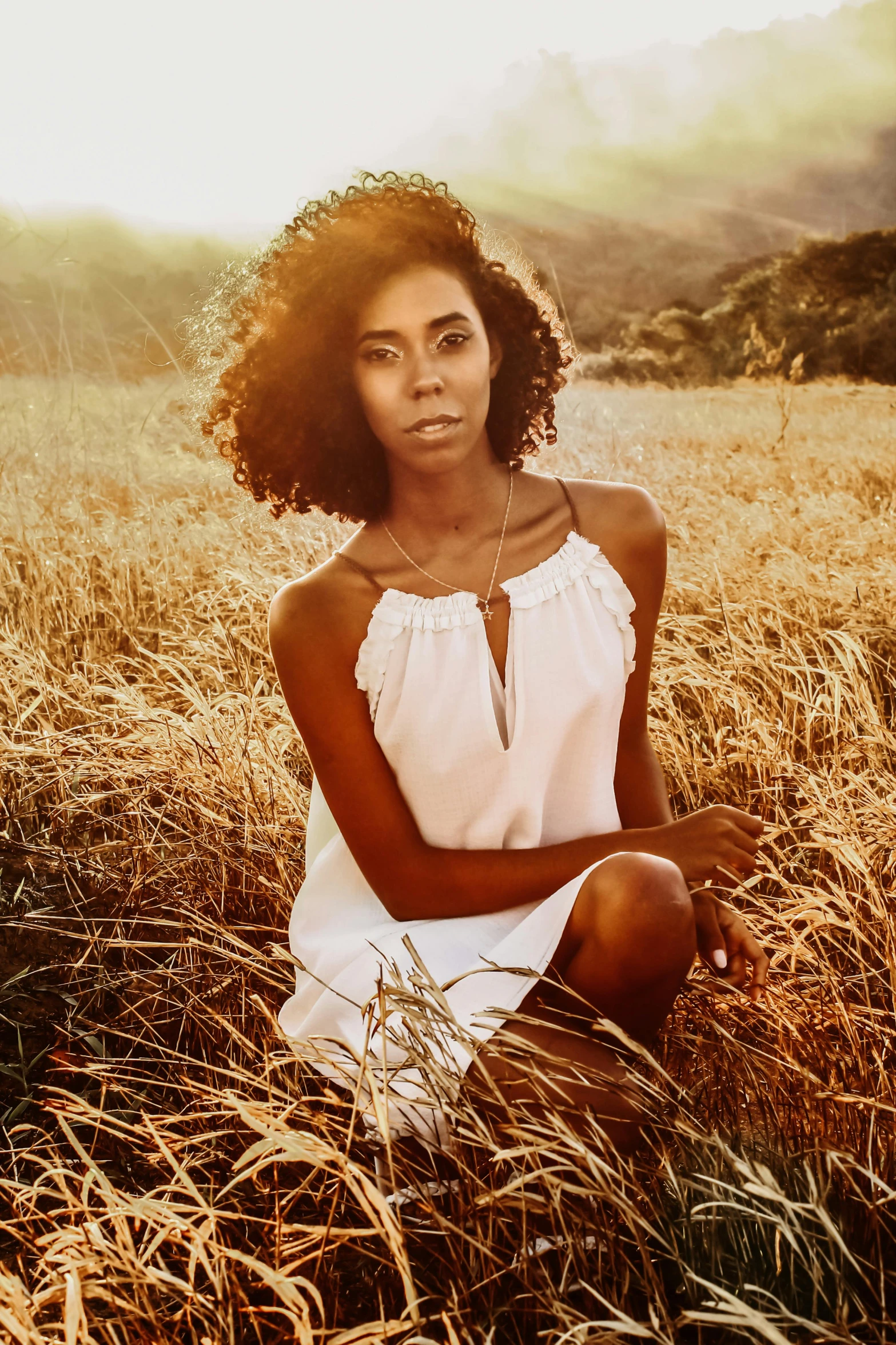 a woman sitting on the ground in tall grass