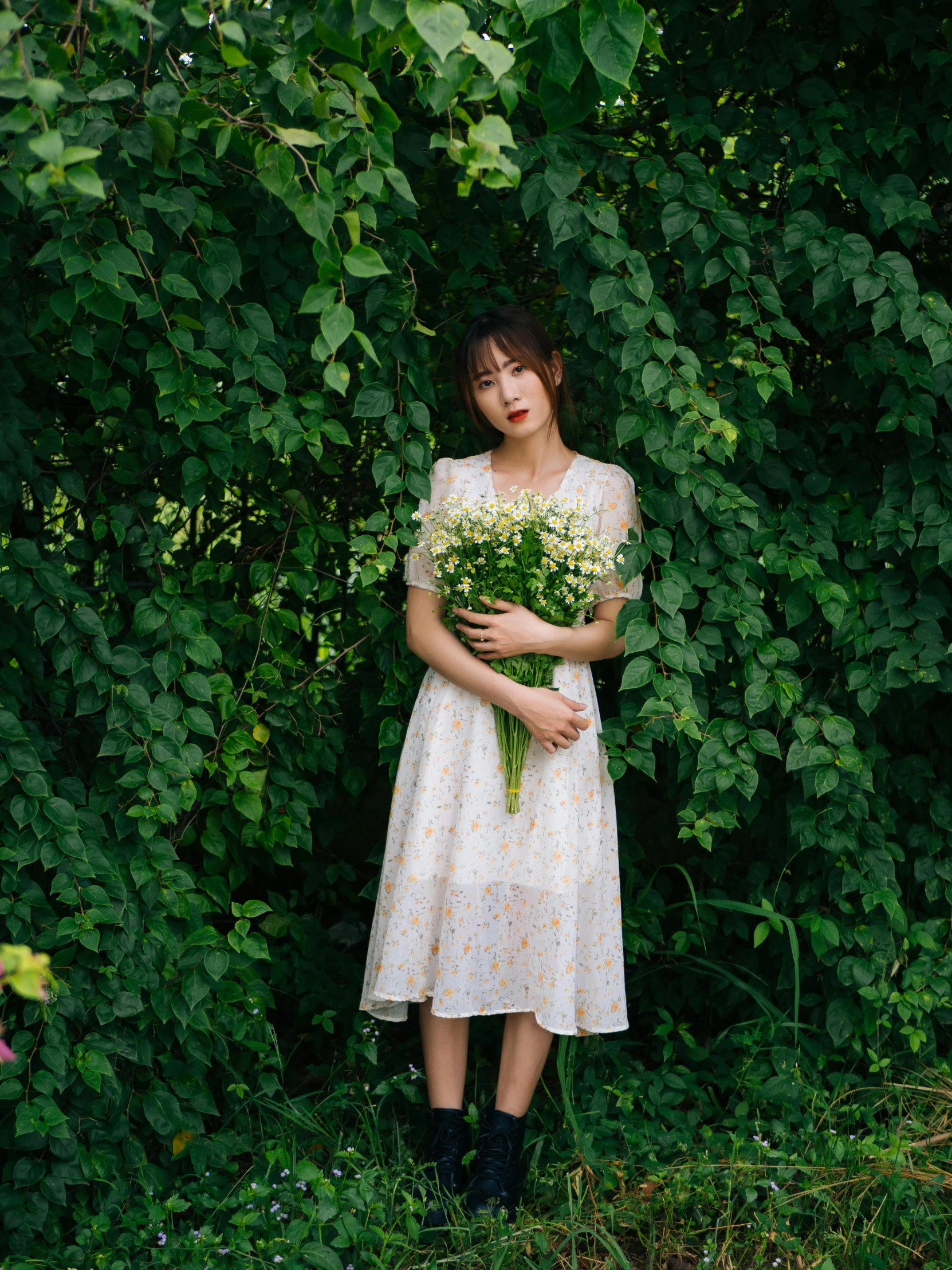 woman holding bouquets in front of plants