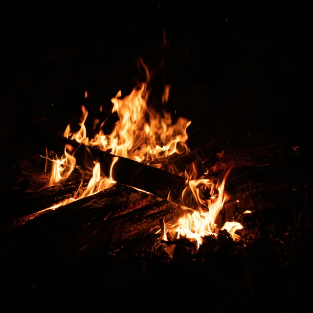 there is a fire and some logs in the dark
