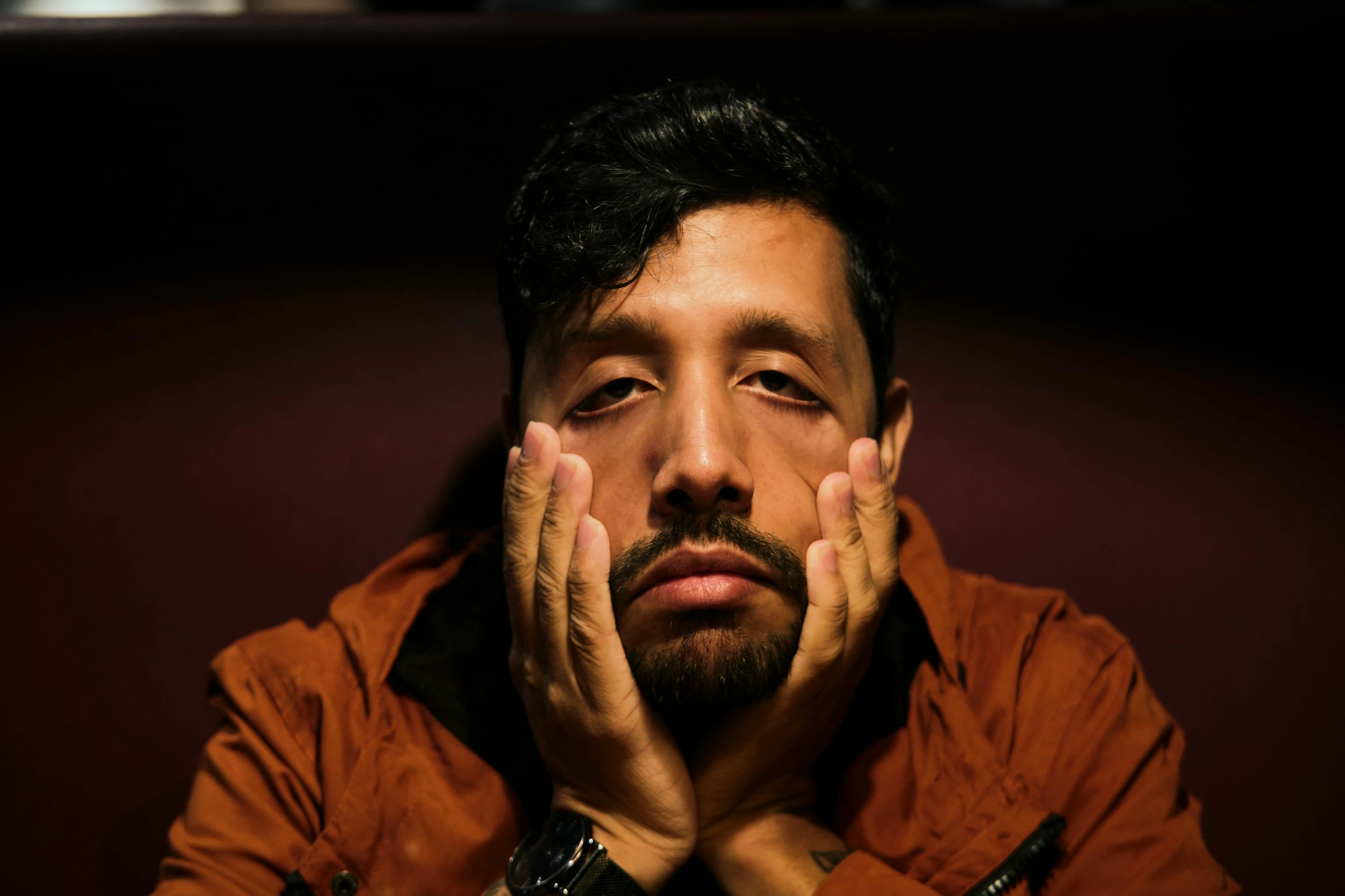 man in brown jacket and clock behind his face