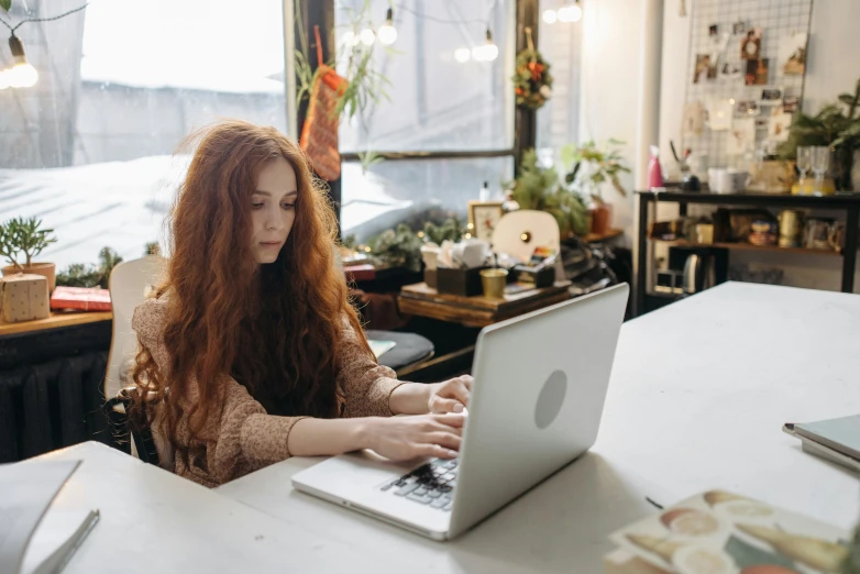 a woman with long hair works on a laptop