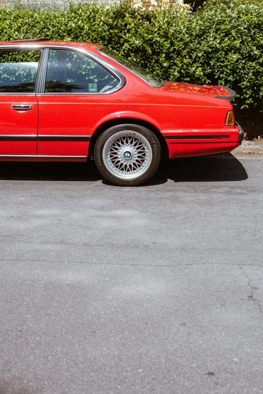 a red car with black accents sitting in a parking lot