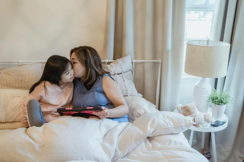 an image of a mother reading to her daughter on the bed