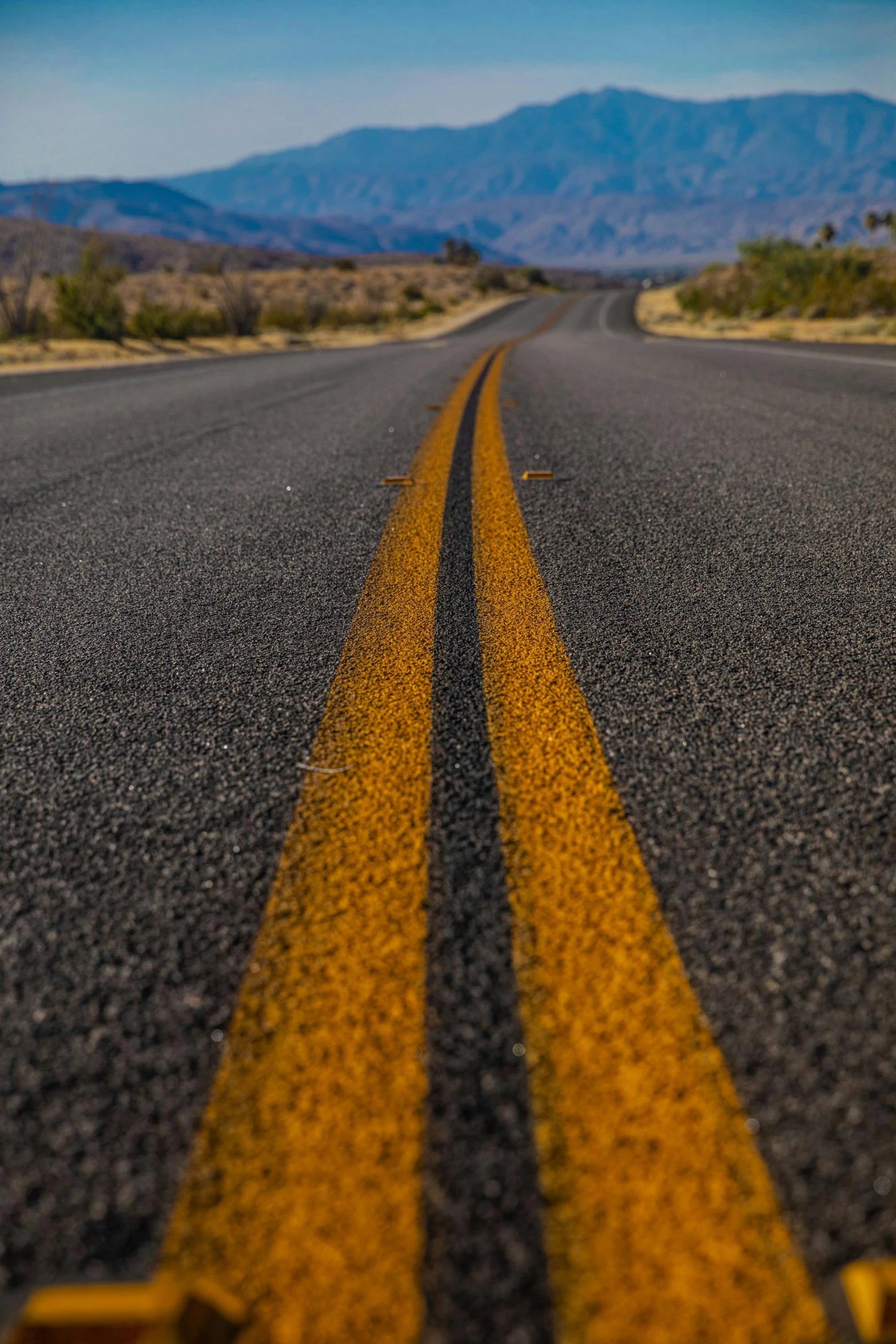 a long black road with yellow painted lines on the middle