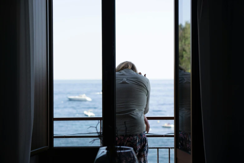 a woman looking out onto a lake from her house