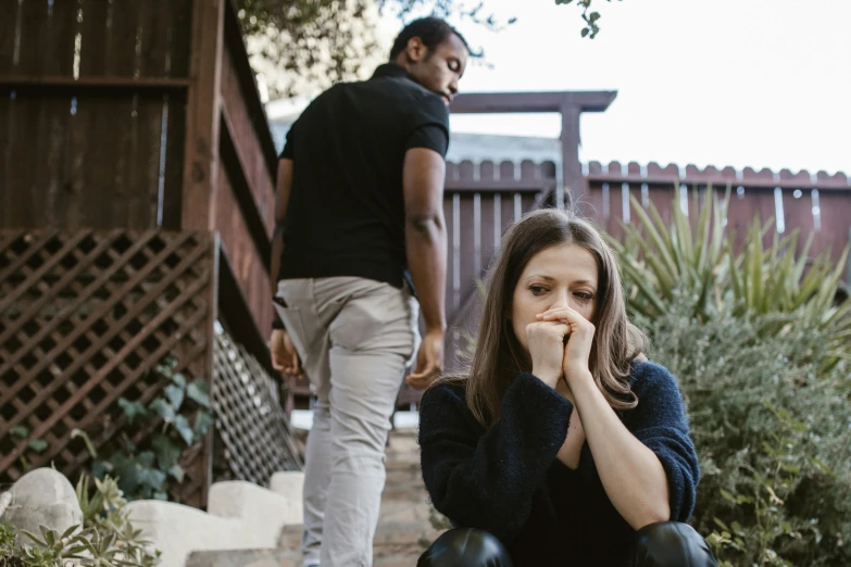 a woman sitting on the ground, with a man walking up to her