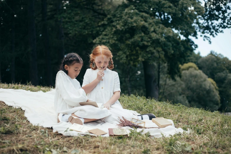 two girls sitting on a blanket outside