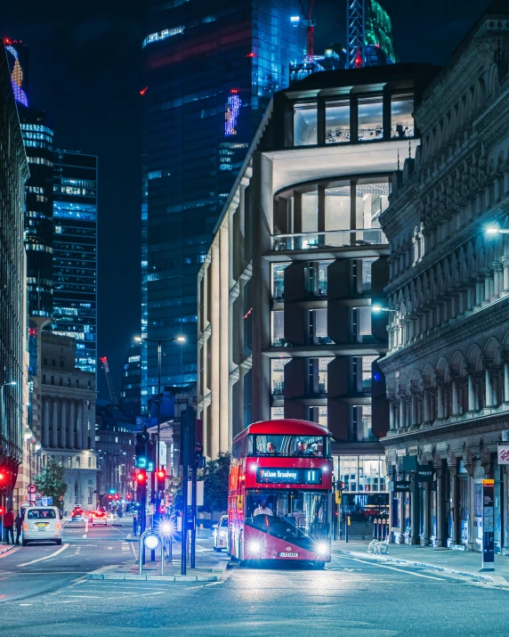 two double decker buses on a city street at night