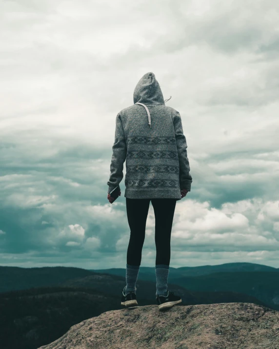 a person standing on top of a large hill with mountains in the background