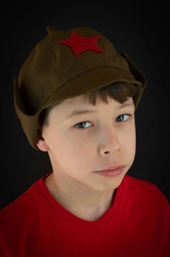 a boy is in a red shirt wearing a brown hat