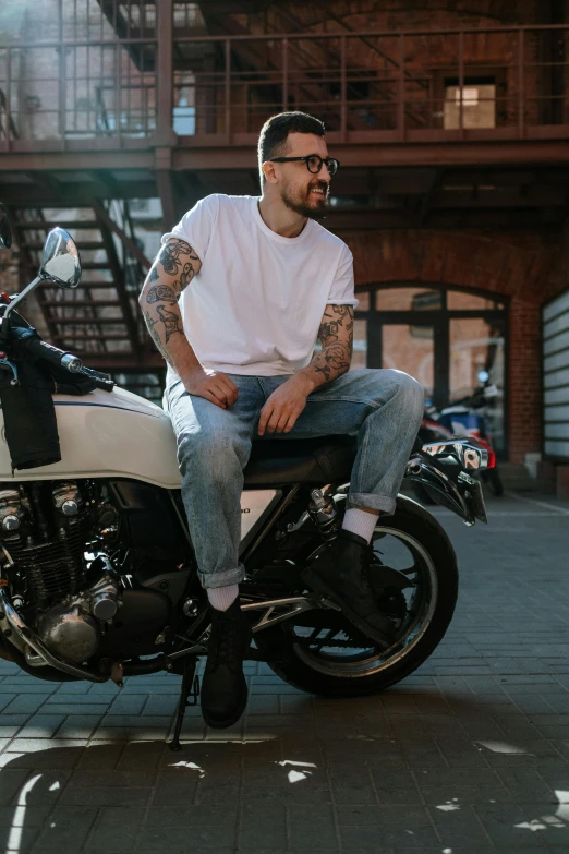 a man in glasses and a white shirt is sitting on a motorcycle