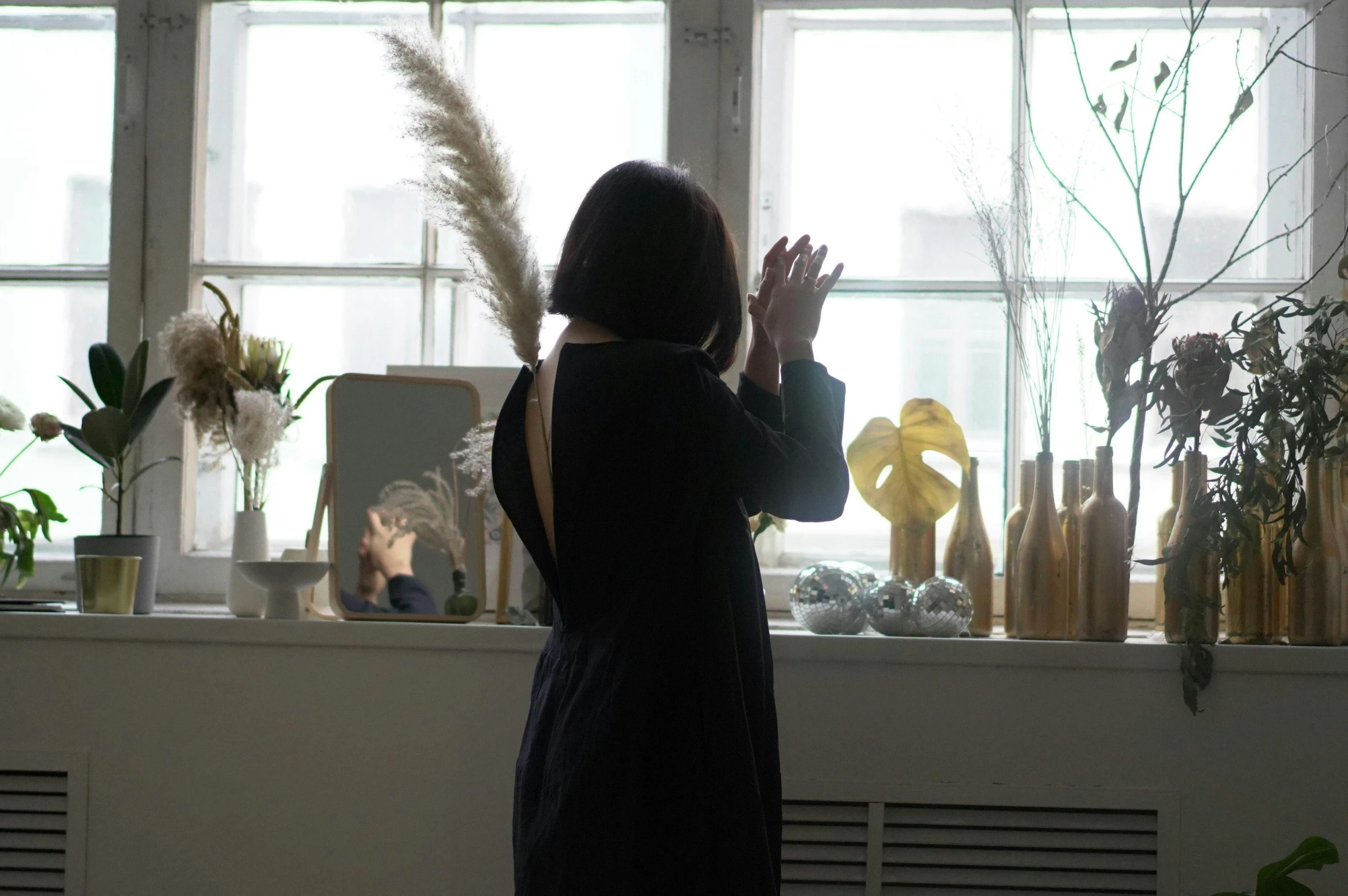 a woman standing in front of a window holding a hand up