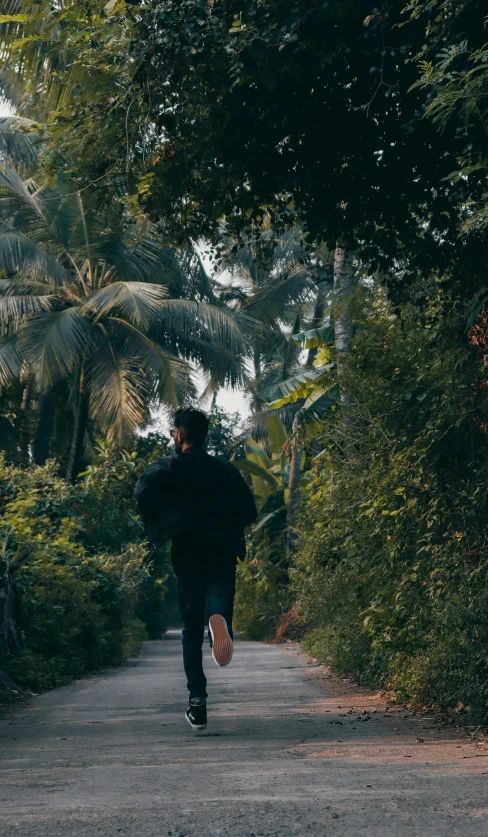 a person runs down a paved street in a wooded area