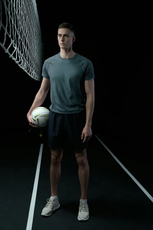 a young man is standing on a tennis court holding a ball