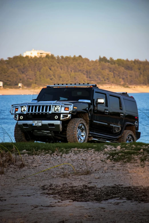 a black hummer truck parked next to the water