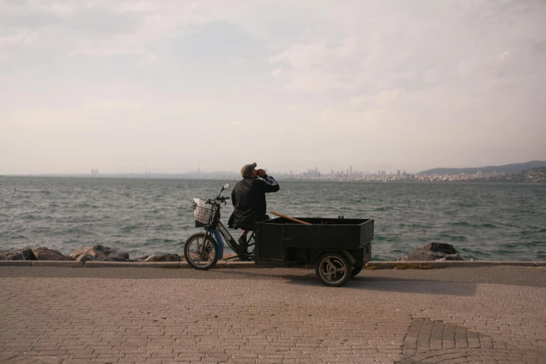 a man on a bike next to the ocean taking a po