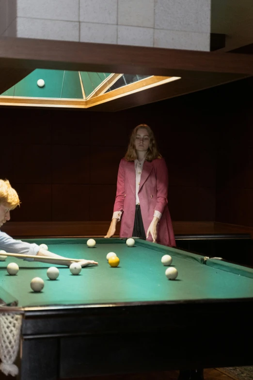 a woman and some young men playing a game of pool