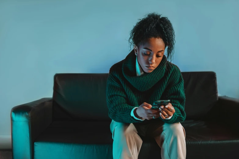 a woman sitting on a couch with a cellphone