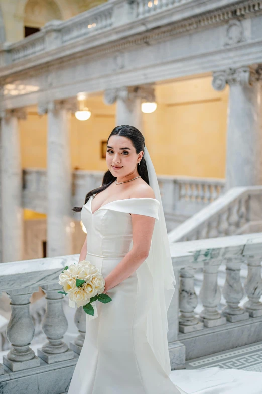 a beautiful woman dressed in a wedding dress holding a bouquet