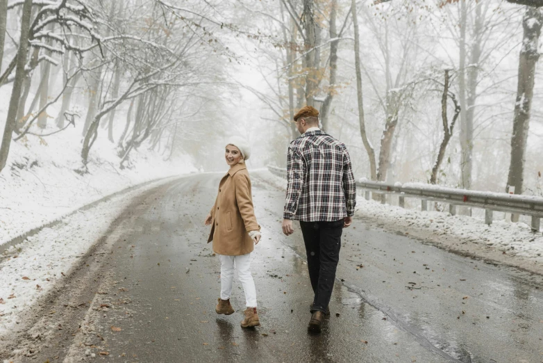 the man and woman are walking down the snowy road