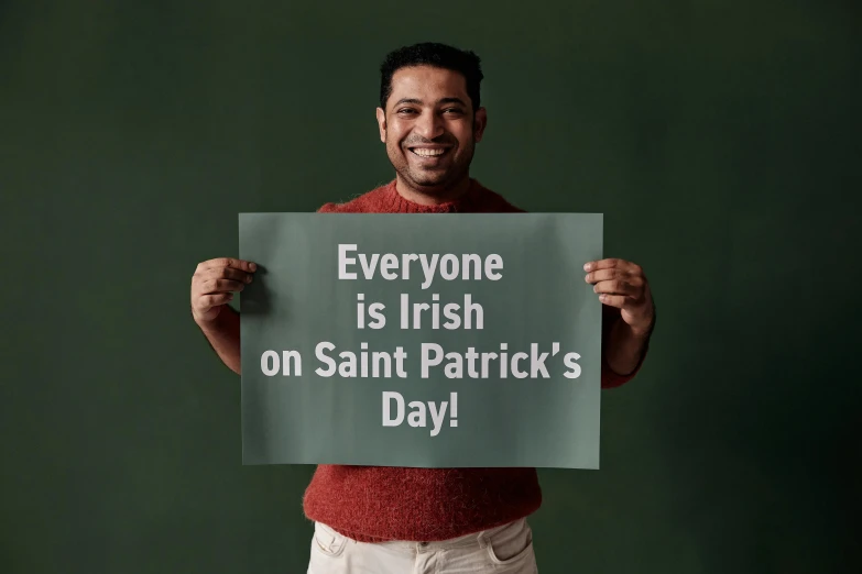 man in sweater holding up sign that says everyone is irish on saint patrick's day