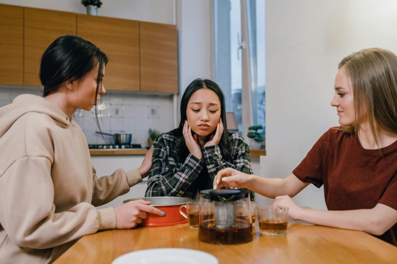 three women are sharing food while one woman is on her phone