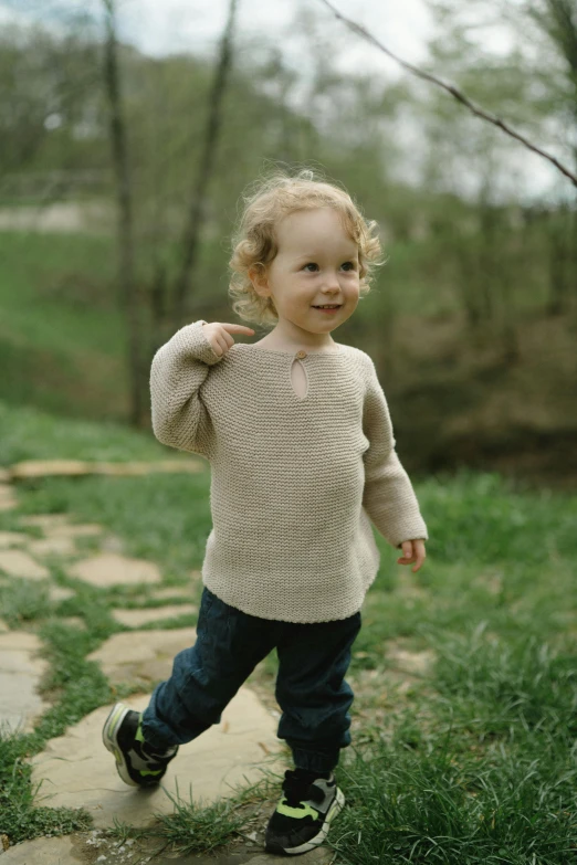 the little girl is walking through the park