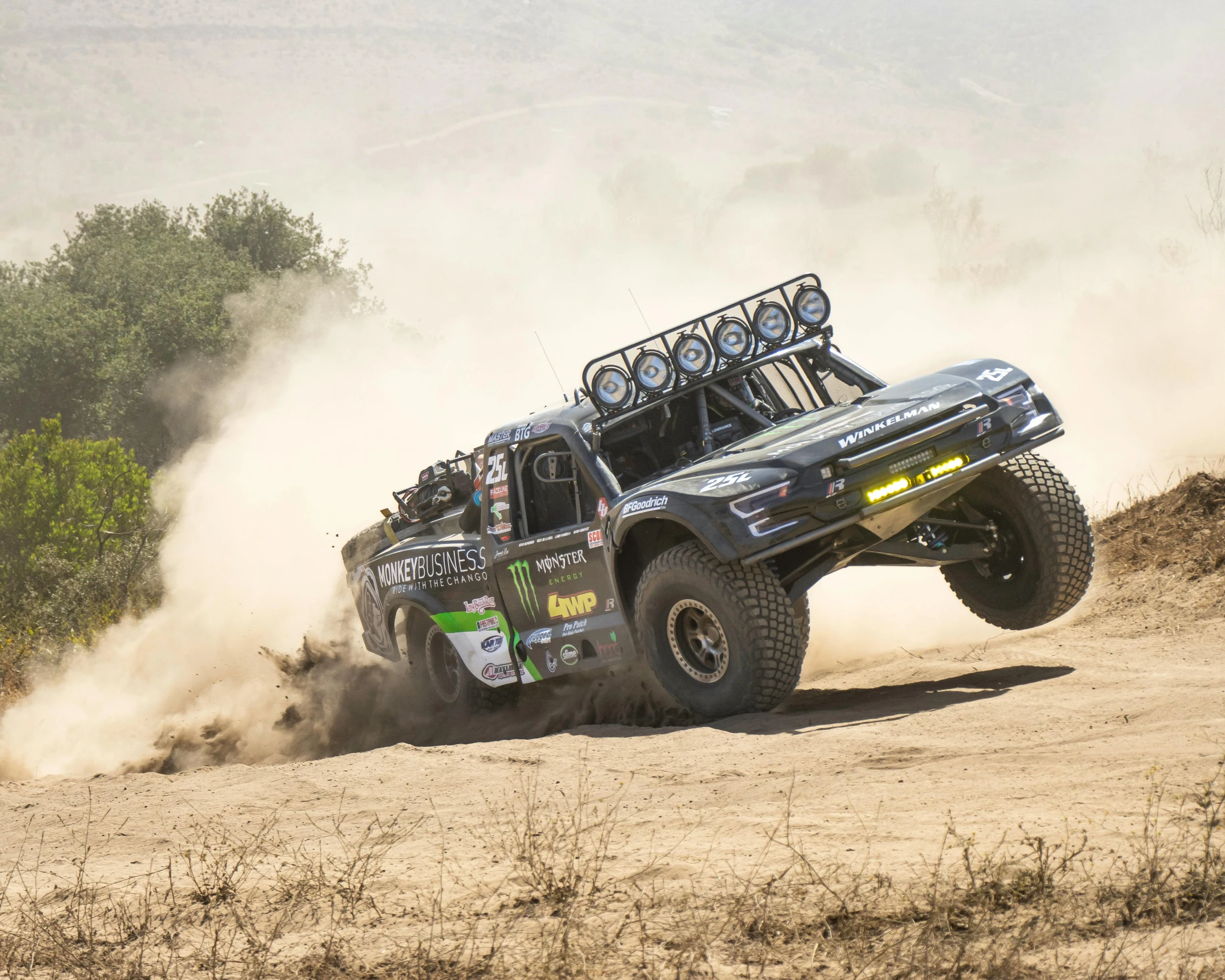 a monster truck makes a jump on a dusty road