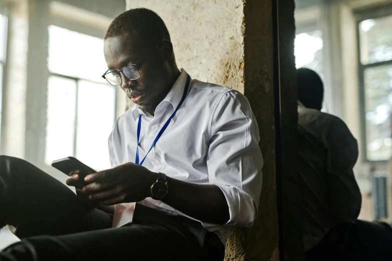 a man is sitting while looking at his phone