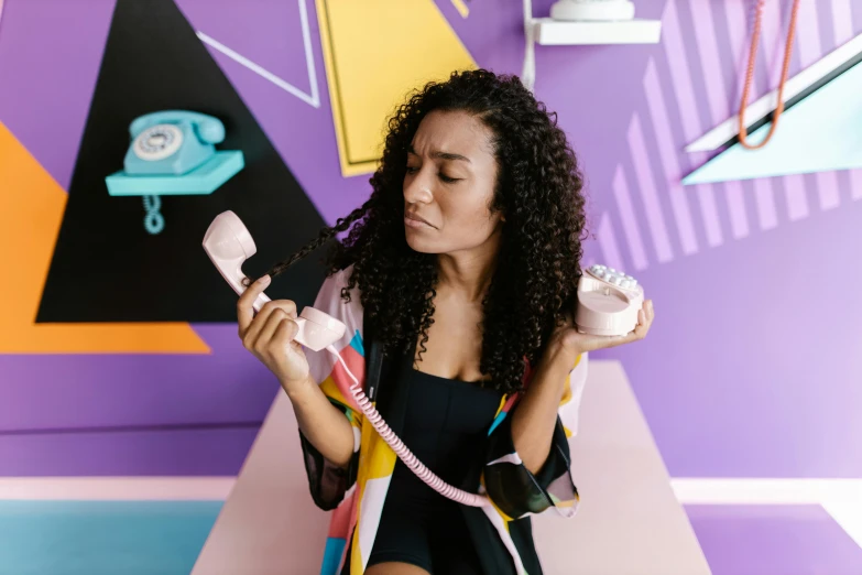 a woman standing in front of a colorful wall holding a telephone